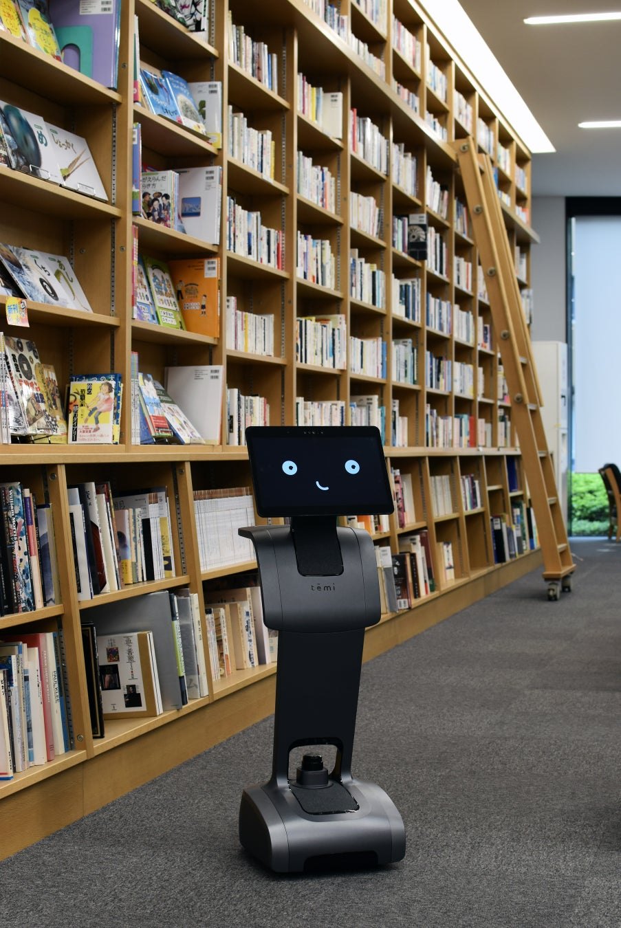 木の書架に和書がぎっしり並ぶ図書館の通路に、目を表示した temi が立っている